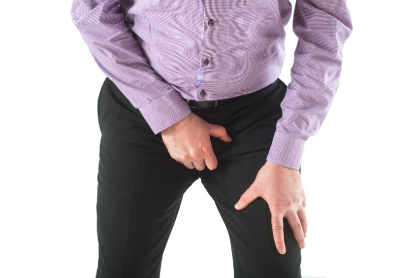 Man holds crotch over trousers