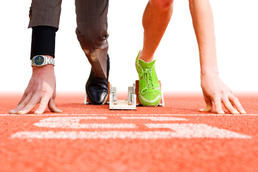 Two people ready for a race, one in a suit, one in athletics grea