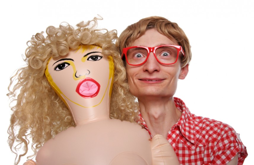 Man with glasses stands next to a blow up doll!