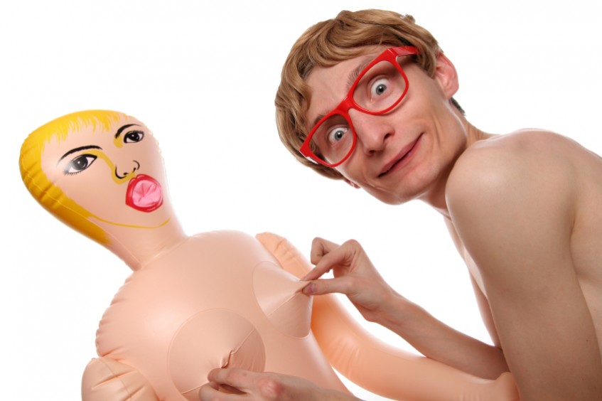 Bespectacled man tweaking nipples of rubbish looking sex doll