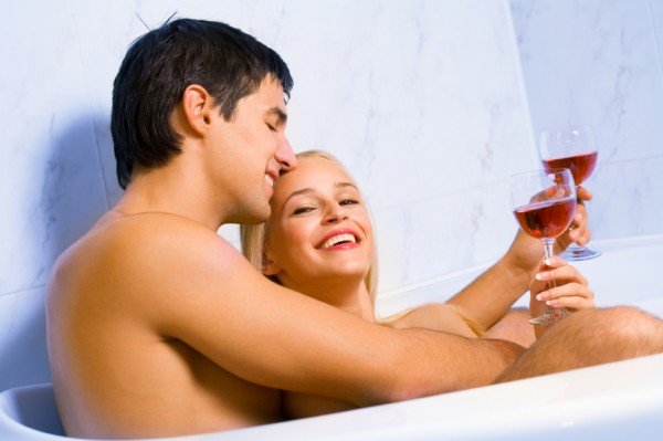 Young happy amorous couple celebrating with redwine at bathroom