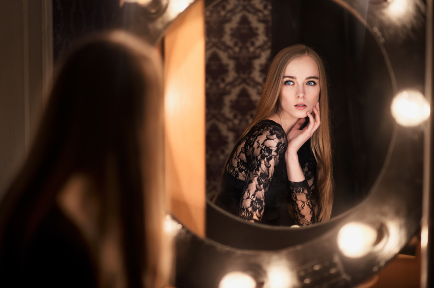 Beautiful fashion model woman posing near the mirror