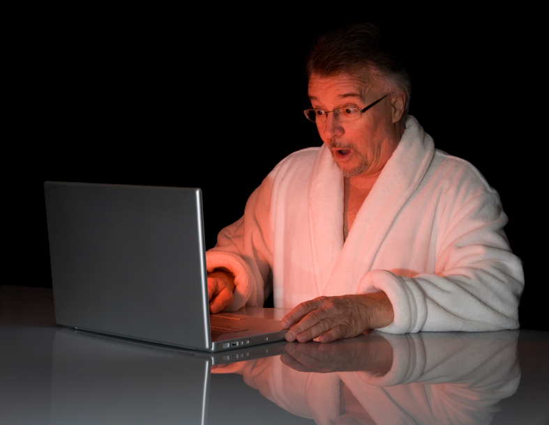 Man in bathrobe looks at laptop