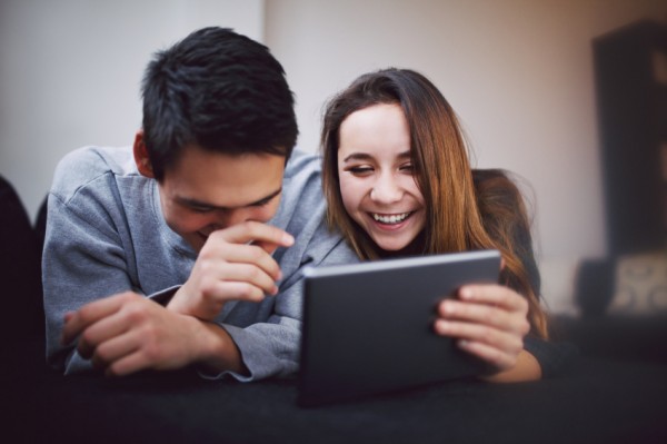 Man and woman laughing over a tablet