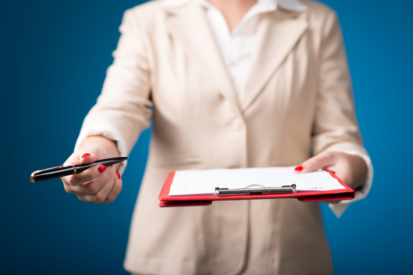 A woman in a suit stands with a clipboard