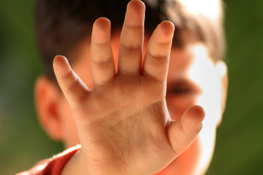 Child with hand in front of face