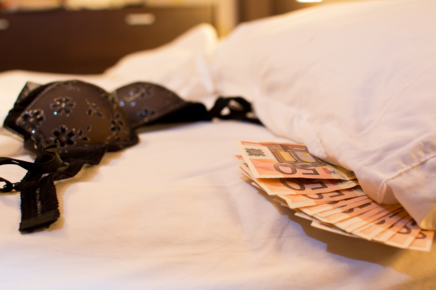 Lingerie and money on a white bed sheet