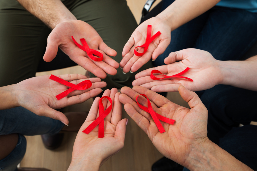 Close-up Of People Holding Red Aids Awareness Ribbon On Palm
