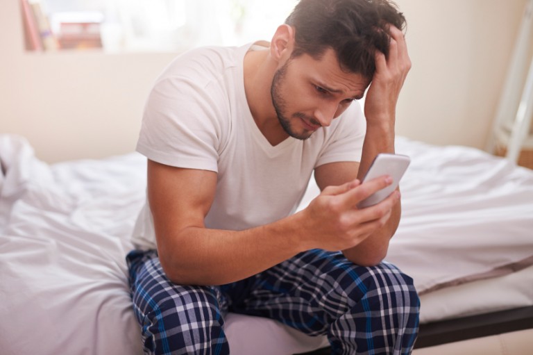 Stressed man looking at mobile phone