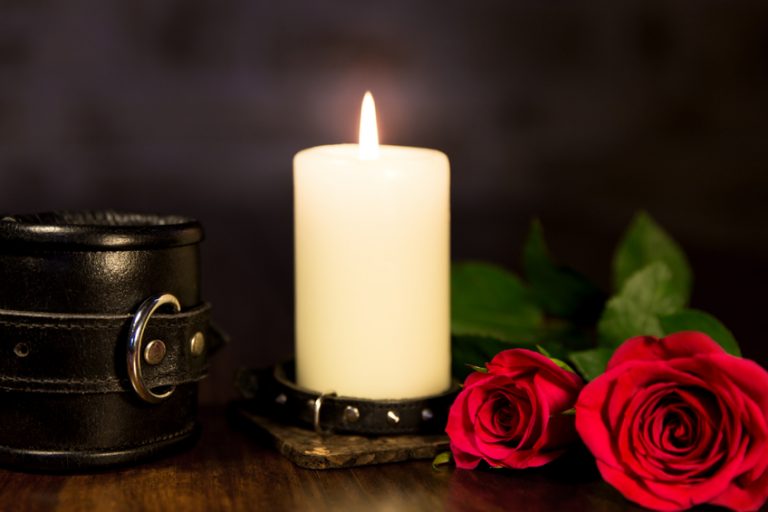 A candle on a table, alongside a cuff, in a BDSM coffee shop