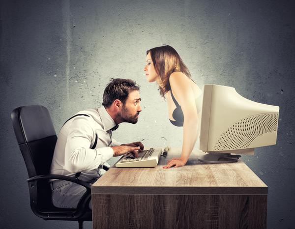 A man sits at a computer enjoying webcam sex