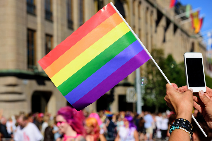 Pride flag and spectator taking pictures with mobile phone