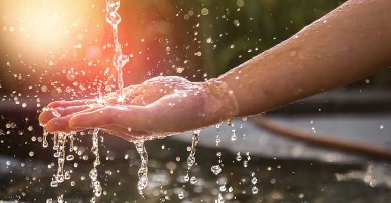 Hands with water splash, backlit by the evening sun.