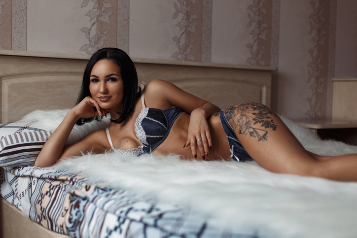 Beautiful girl with a tattoo in lingerie on the body lying on the bed
