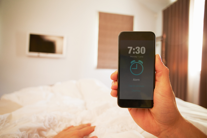 Point Of View Image Of Person In Bed Turning Off Phone Alarm