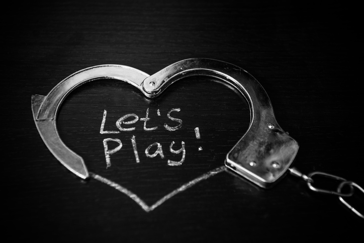 Metal handcuffs on dark background with bdsm caption