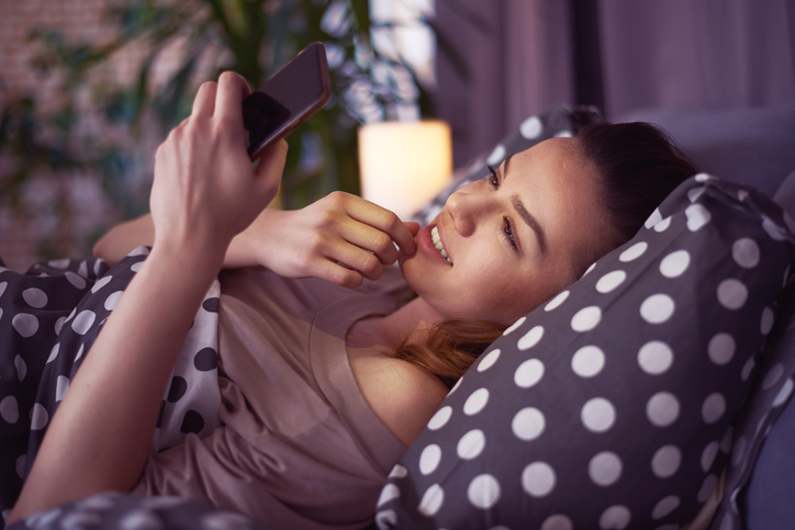 Woman looking at phone in bed