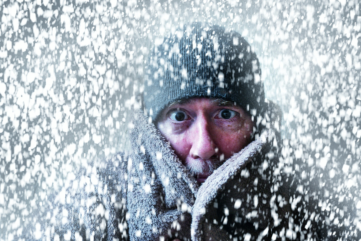 Wintery scene of a man shivering in a snow storm