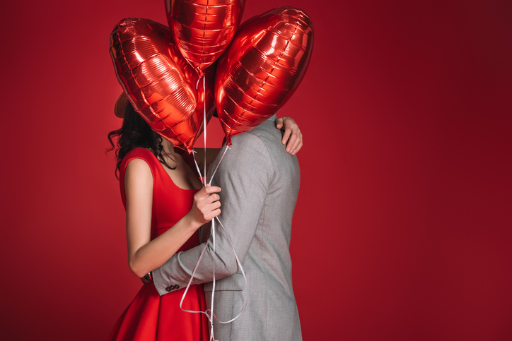 couple kissing behind balloons