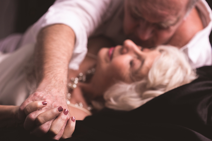 Senior man embracing mature woman, lying on bed