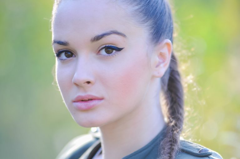 Girl near the brick wall in military style.