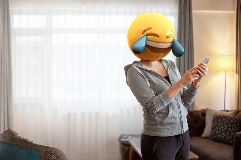 Woman wearing emoji masks while looking at her phone.