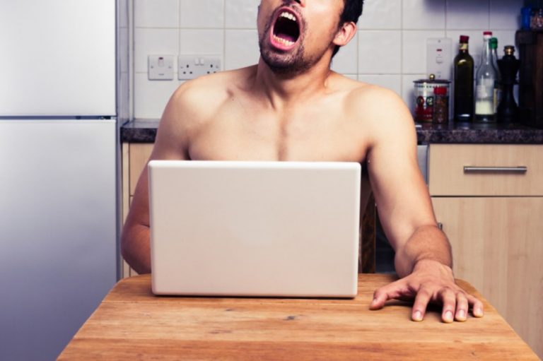 Man sits at table jerking off over a laptop