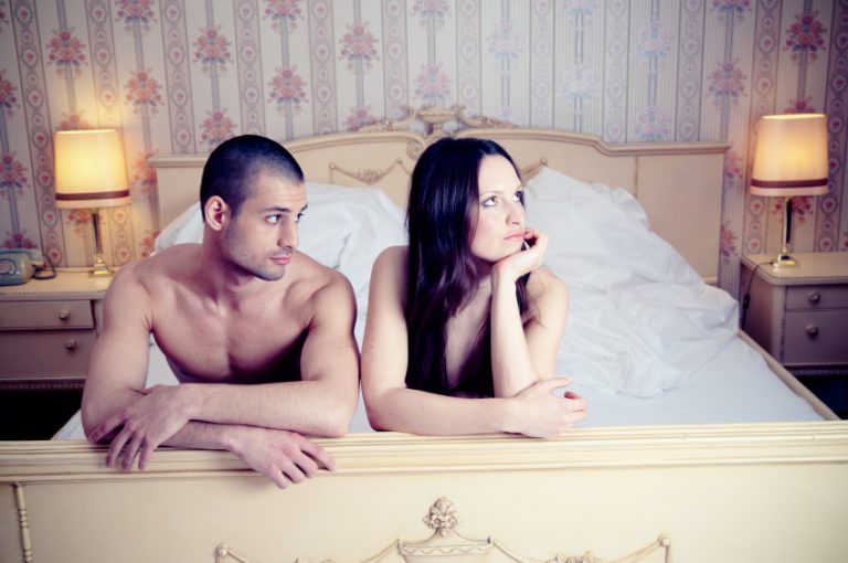 An unhappy man and woman lying on a bed