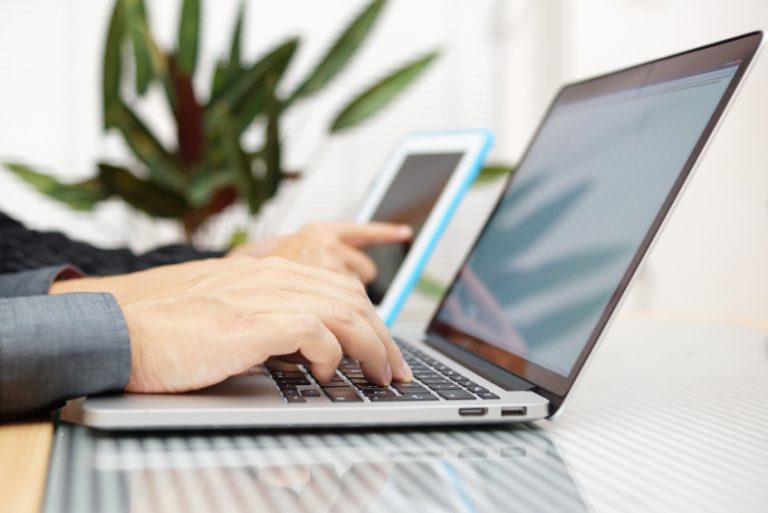 businessman in office typing on keyboard with businesswoman using tablet pc in background