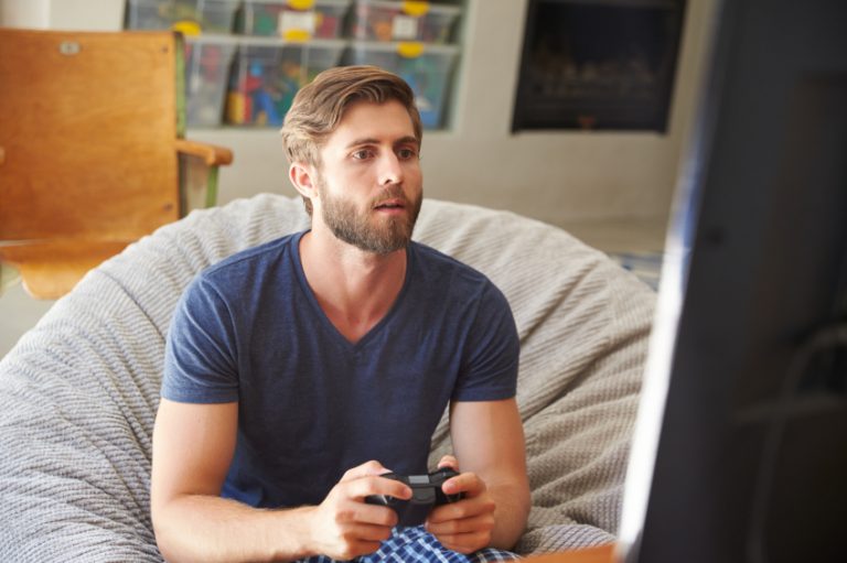 Man Wearing Pajamas Sitting In Chair And Playing Video Game