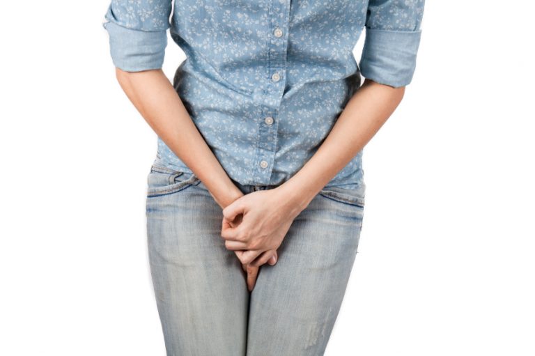 Close up of a woman with hands holding her crotch isolated in a white background