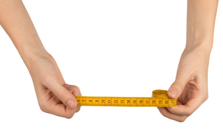 A man holds out a measuring tape to find out his penis size