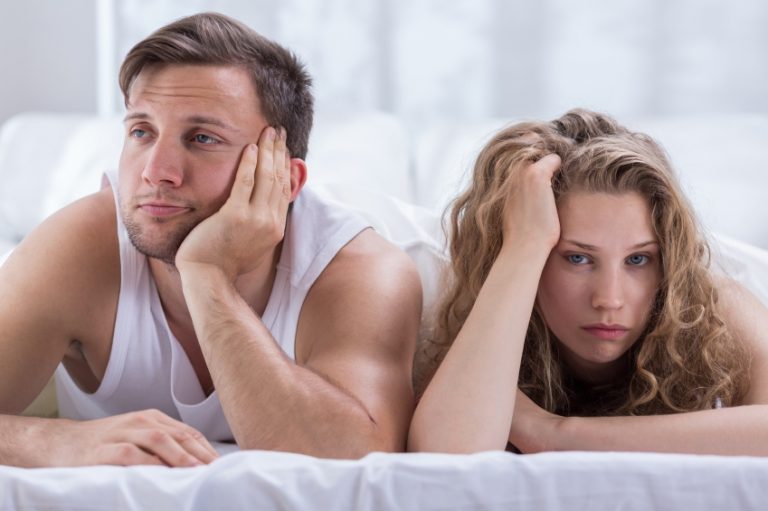 A man and woman lying in bed feeling disappointed with the vanilla sex they are having