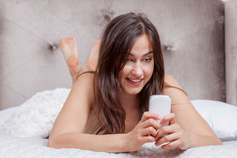Sexy woman on bed looking at her phone