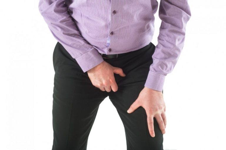 Man hold genitals over trousers