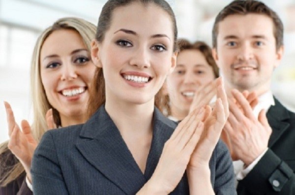 A group of people clapping at the camera